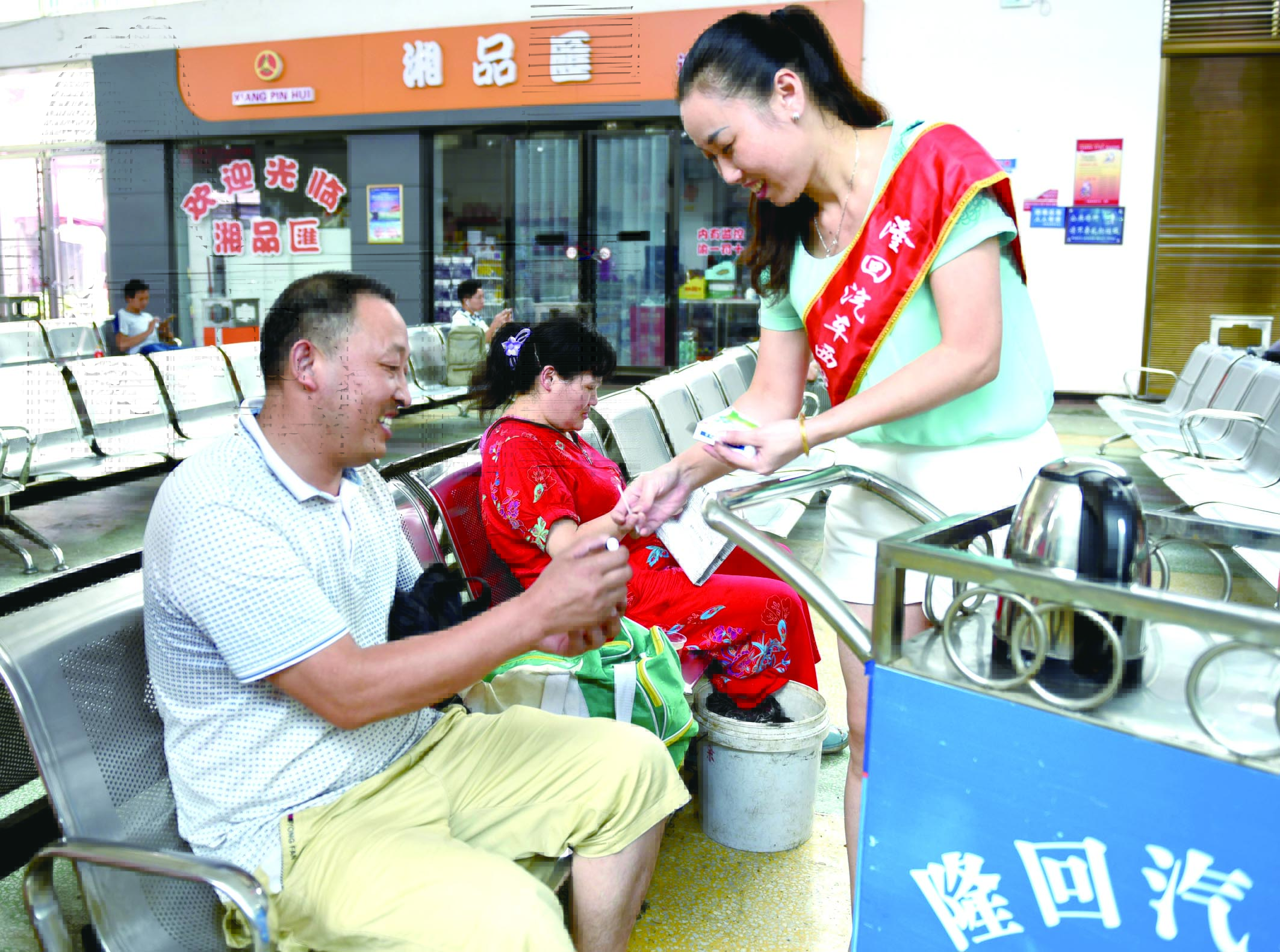 隆回分公司汽車西站工作人員正在為旅客免費(fèi)贈送藿香正氣水。